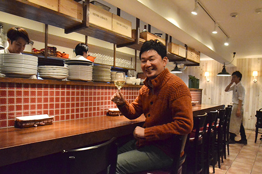 樽生ワインを片手に微笑む藤丸さんと、後方でなぜか笑いをこらえるスタッフ。(C)NaraYuko
